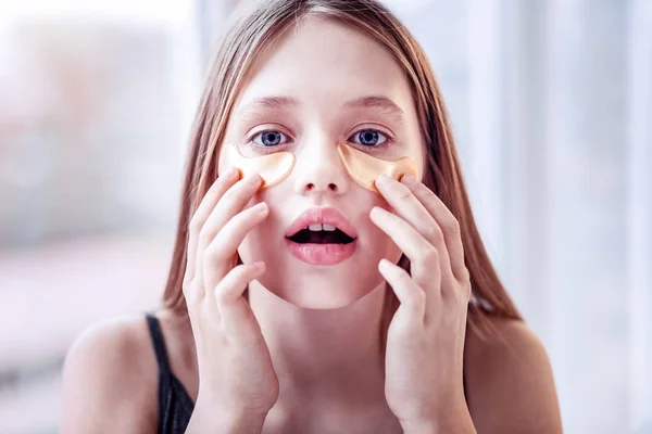 Astonished positive girl putting eye patches for hydrating — Stock Photo, Image