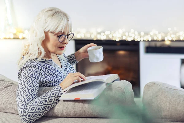 Trevlig positiv kvinna läser en bok hemma — Stockfoto