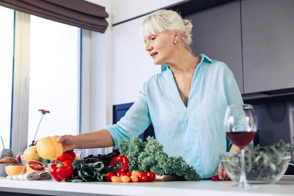 Positive blonde woman taking a yellow pepper