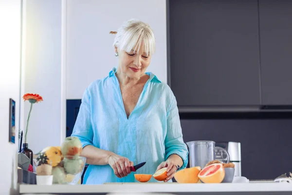 Mujer de edad positiva mirando a la naranja —  Fotos de Stock