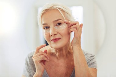 Yüzünde göz düzeltme eklerinin uygulanmasıyla olumlu neşeli kadın