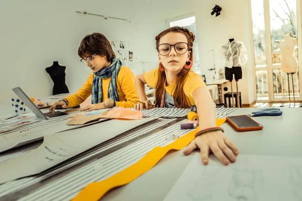 Cute girl wearing glasses taking paper with sketches — Stock Photo, Image