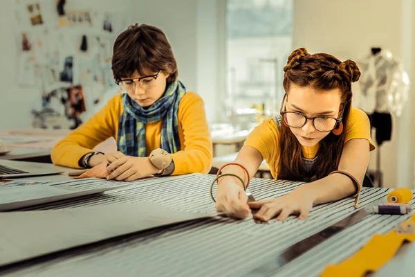 Brother and sister attending design school using striped fabric — Stock Fotó