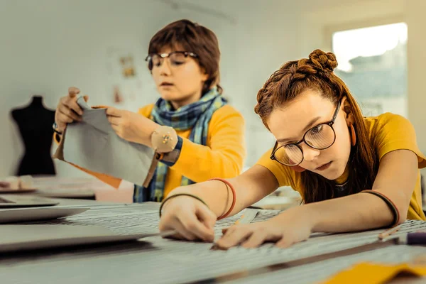 Futuri stilisti che utilizzano righelli mentre misurano i tessuti — Foto Stock