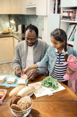 Sevimli kız babası sandviç yapmak yardımcı olurken neşeli hissediyorum