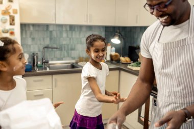 Little cute daughter having fun while using flour when cooking