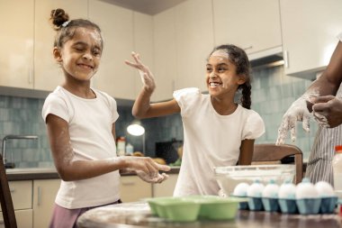 Mutfakta un ile oynarken neşeli gülen kardeşler