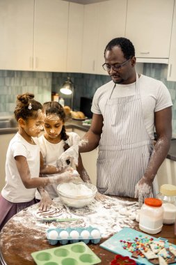Baba ve iki kız hafta sonu sabah kek pişirdiğini