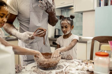 İki kızı çikolatalı pasta yaparken neşeli hissediyorum