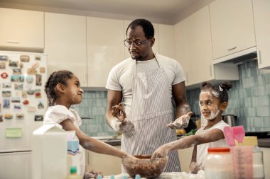 Afrikalı-Amerikalı adam yemek çikolata pasta kızları ile önlük