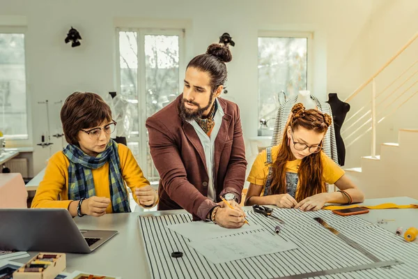 Темноволоса бородата дизайнерка з зачіскою, що працює біля своїх дітей — стокове фото