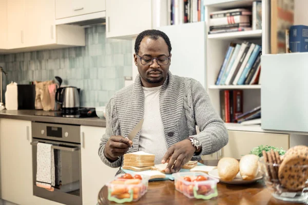 Marido maduro sintiéndose ocupado mientras hace sándwiches para su familia — Foto de Stock