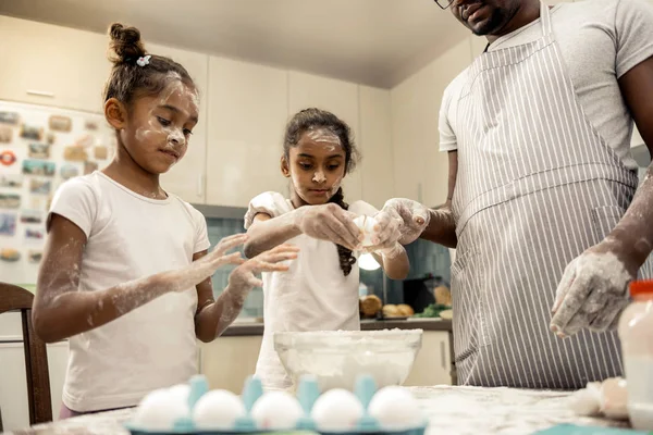 Δύο μαθήτριες χτυπώντας τα αυγά ενώ κάνοντας cupcakes με πατέρα — Φωτογραφία Αρχείου