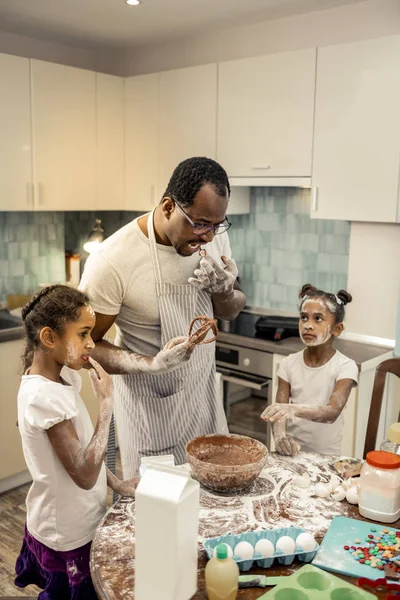 Μικρές κόρες έχοντας τα πρόσωπά τους σε αλεύρι μαγείρεμα με τον πατέρα — Φωτογραφία Αρχείου