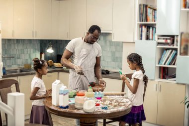 Babası ile kek pişirdiğini beyaz gömlek ve etek giyen kızları