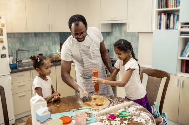 Domates sosu. Büyük kızı birlikte pişirme pizza üzerine domates sosu giyerken neşeli hissediyorum