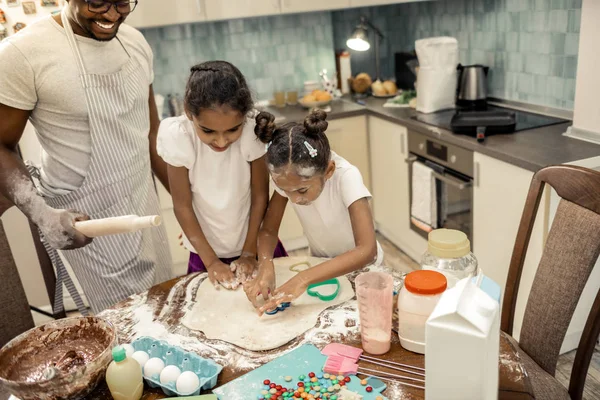 Ακτινοβολούν πατέρας βλέποντας τα χρήσιμες κορίτσια του σχηματίζοντας μπισκότα — Φωτογραφία Αρχείου