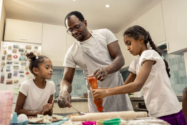 Σκούρα μαλλιά πατέρα και χαριτωμένο κόρες μαγείρεμα πίτσα για δείπνο — Φωτογραφία Αρχείου