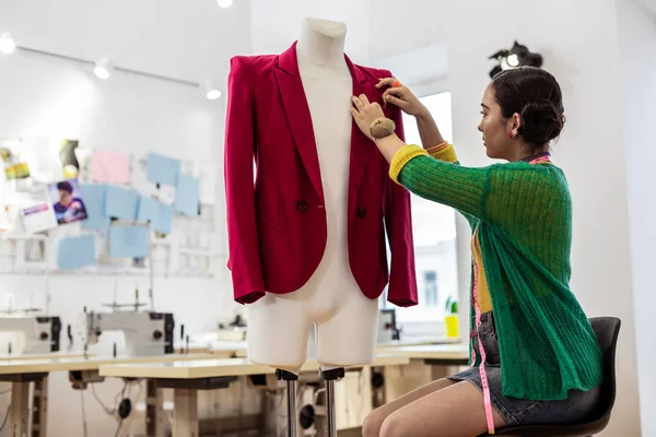 Jonge dark-haired ontwerper met een pin kussen op haar hand werkt aan een model — Stockfoto