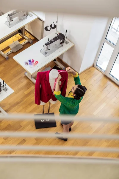 Dark-haired asian stylist in a short skirt working with a dummy — Stock fotografie