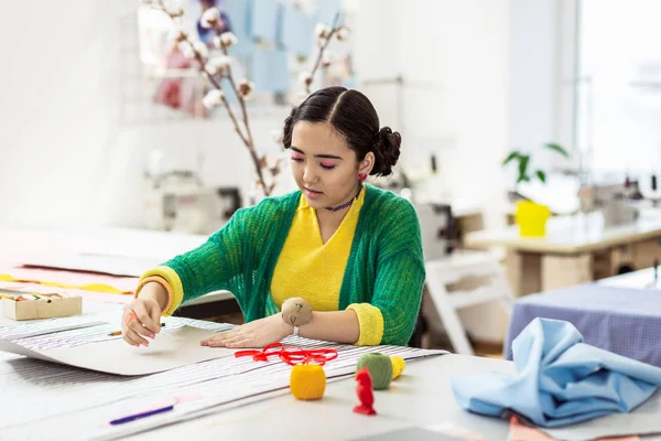 Hübsche brünette asiatische Schneiderin mit hellem Nagellack arbeiten mit einem Muster — Stockfoto