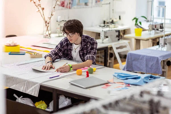 Giovane designer asiatica dai capelli scuri con un orologio verde che lavora in uno studio — Foto Stock