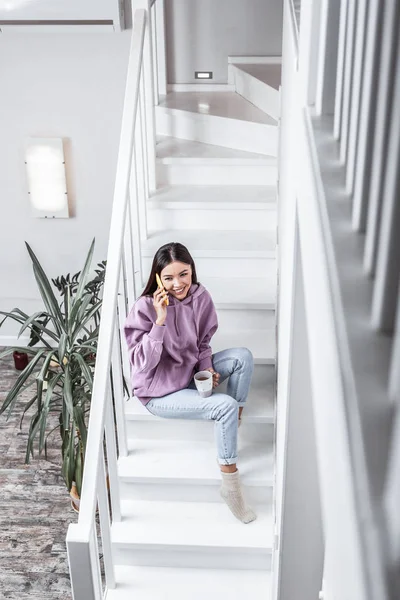 Vista superior de la mujer joven sentada en las escaleras en la casa espaciosa luz — Foto de Stock