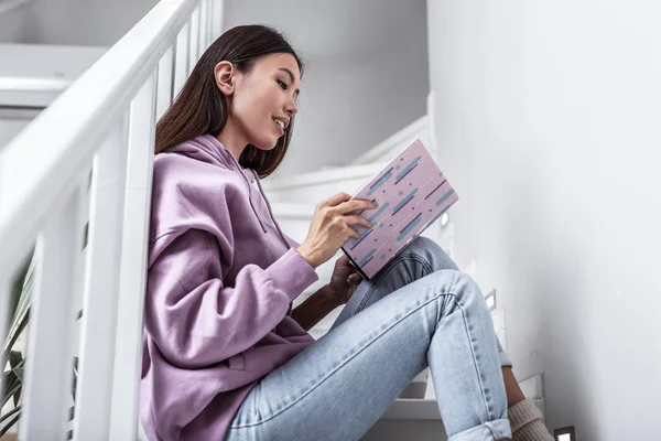 Ελκυστική γυναίκα που κάθεται σε σκαλοπάτια διαβάζοντας ενδιαφέρον βιβλίο — Φωτογραφία Αρχείου