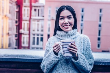 Joyful young woman standing with a cup