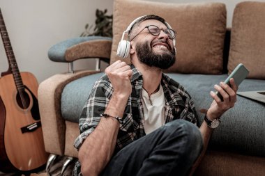 Positive bearded man wearing his white headphones