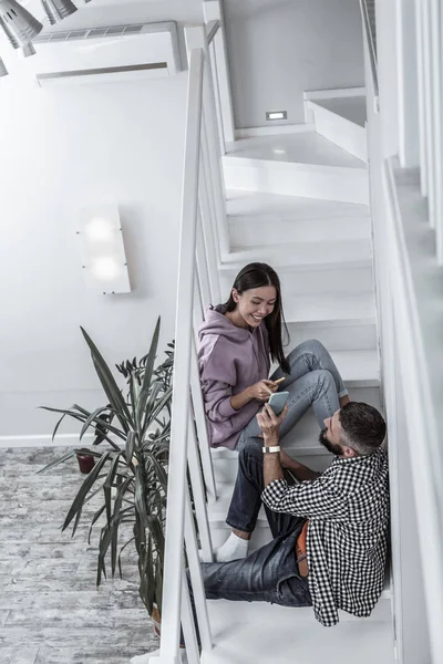 Unga snygga paret sitter på trappan i sin ljusa rymliga hem — Stockfoto