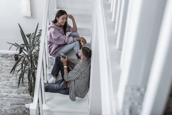Мила любляча пара розмовляє вдома, сидячи на сходах — стокове фото