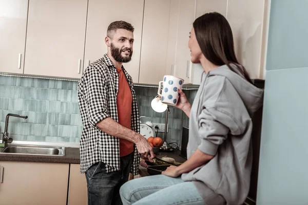 Baard zorgzame man snijden salade staande in de buurt van vrouw drinken tea — Stockfoto