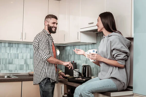 Lycklig kvinna tittar på sin man som torkning lite kött till middag — Stockfoto