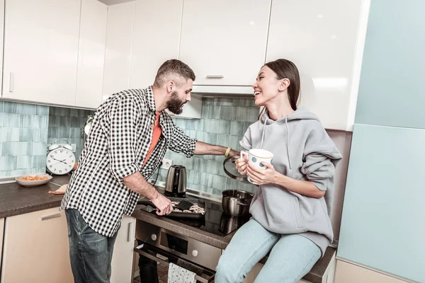 Vrolijke vrouw voelt geweldig kijken naar haar man eten koken — Stockfoto