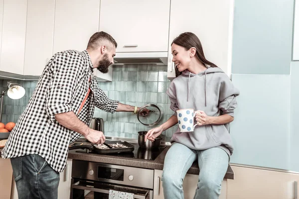 Liefhebbende echtgenoot koken diner op zijn eigen draagkracht in de buurt van vrouw — Stockfoto