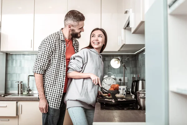 Hombre cariñoso que viene a la cocina donde la esposa cocina la cena — Foto de Stock