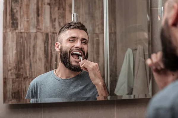 Alegre hombre maduro de ojos oscuros cepillándose los dientes por la mañana — Foto de Stock