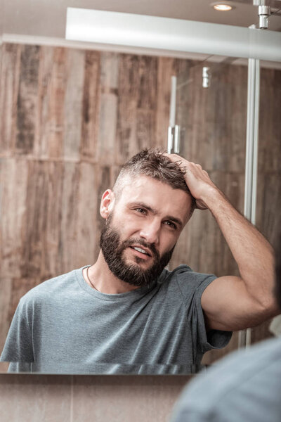 Молодой бизнесмен в серой рубашке смотрит в зеркало
