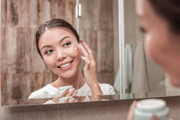 Kellemes, vonzó nő segítségével arckrém, reggel — Stock Fotó