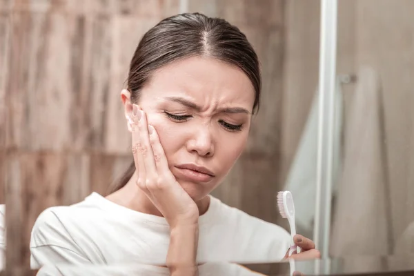 Mörkhårig kvinna med stark tandvärk efter tandborstning dem — Stockfoto