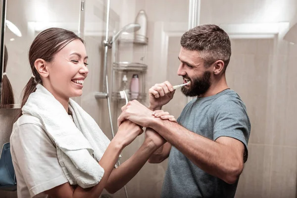 Young loving couple having much fun while brushing teeth together — Stock Photo, Image