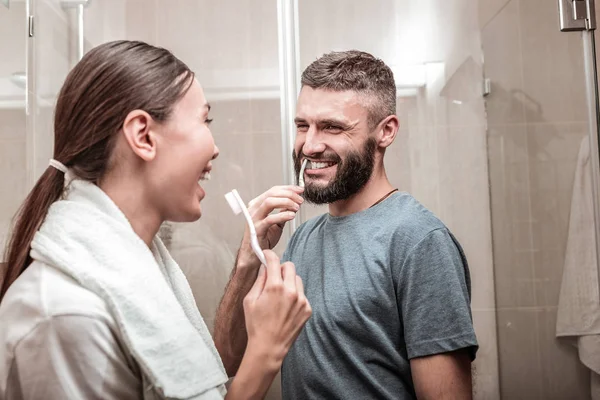 Cute laughing couple fighting for bathroom in the morning