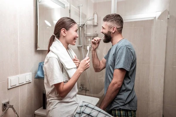 Positive delighted couple brushing their teeth together — Stock Photo, Image