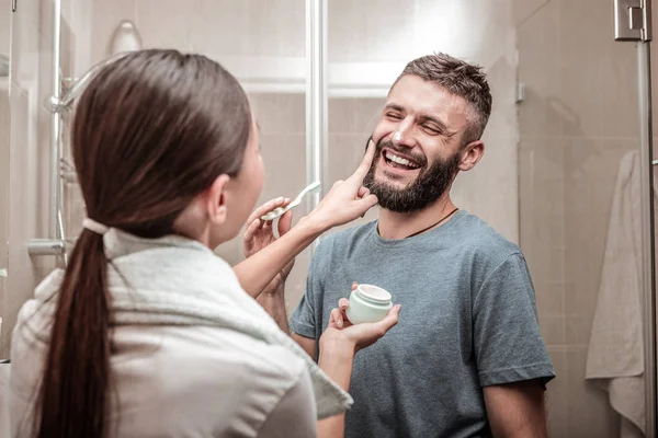 Agradable mujer poner crema en su cara novios — Foto de Stock