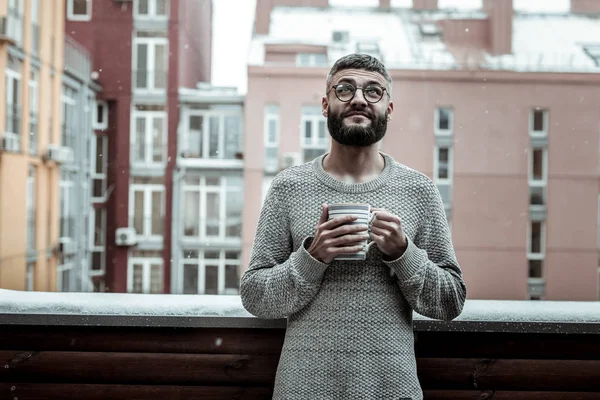 Pěkný vousatý muž dívá na sněhové vločky — Stock fotografie