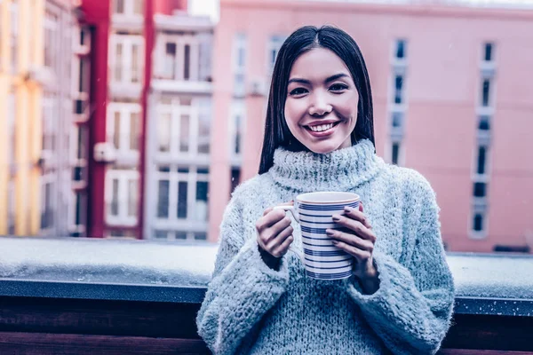 Joyful young woman standing with a cup