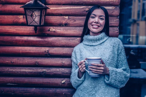 Positive joyful woman standing near the wooden wall — Stock fotografie