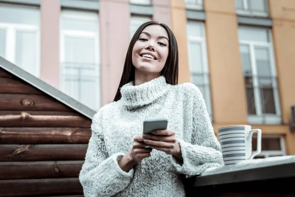Радостная позитивная женщина стоит со своим телефоном — стоковое фото