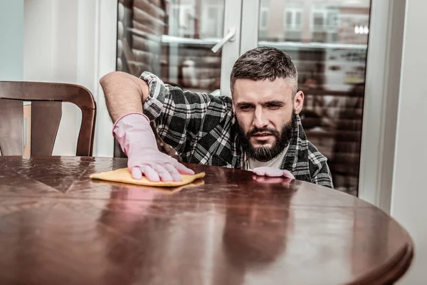 Pleasant nice man cleaning the table in the house — Stock Photo, Image